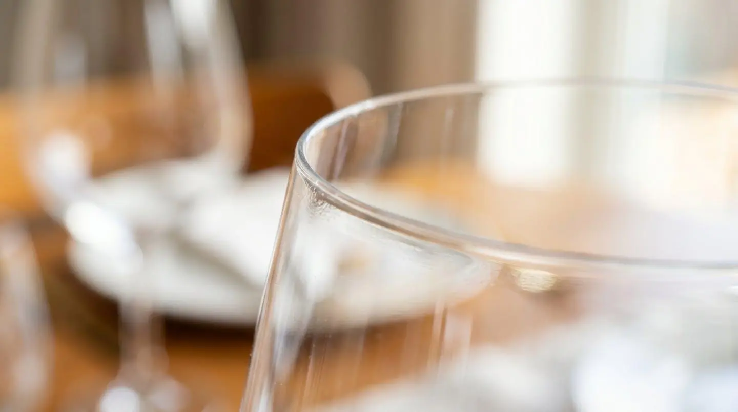 Gros plan sur le bord ultrafin d'un verre en cristallin avec une lumière rasante révélant la transparence du matériau